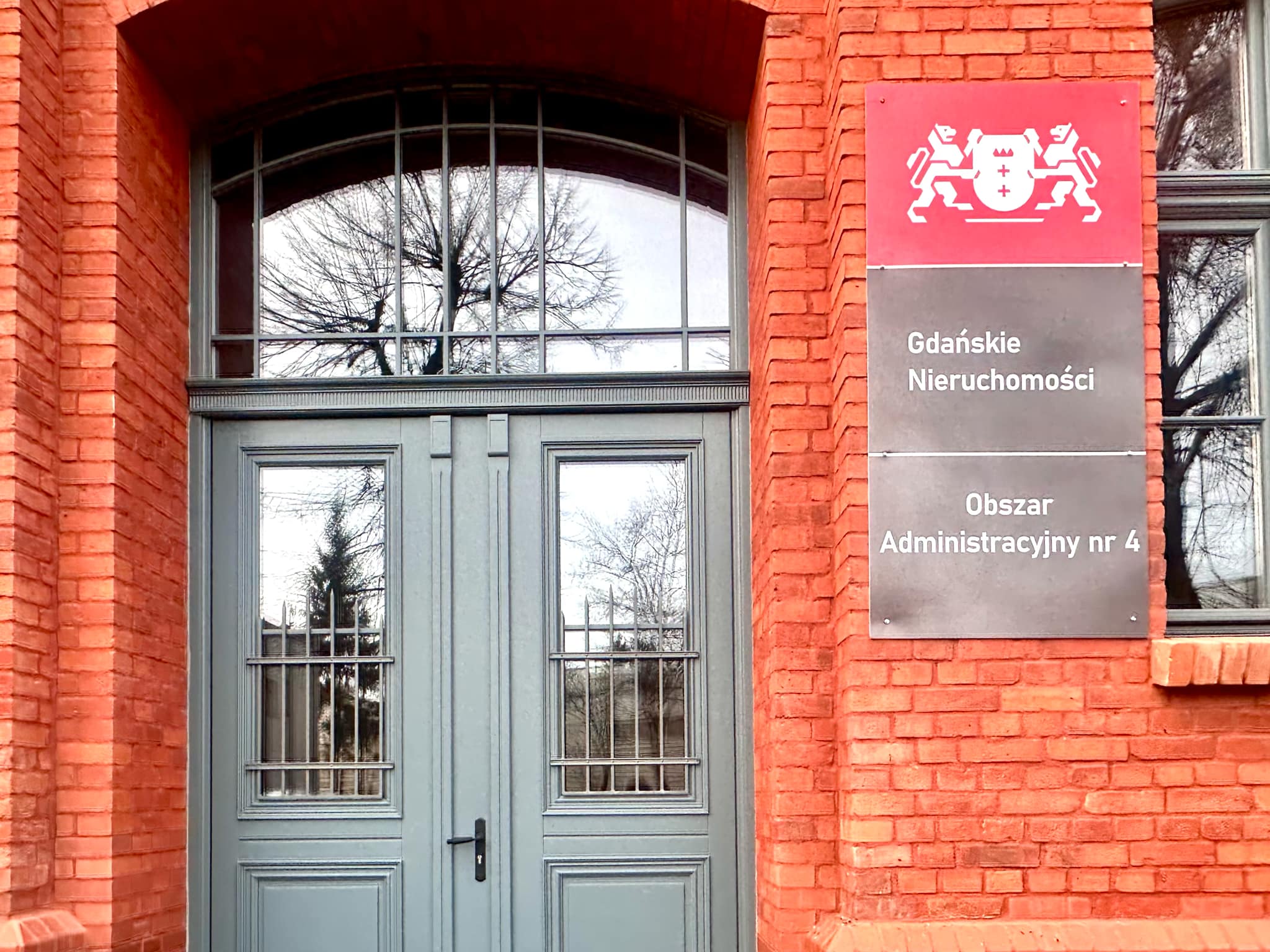 Zdjęcie przedstawia elewację budynku z tablicą z napisem Gdańskie Nieruchomości Obszar Administracyjny nr 4