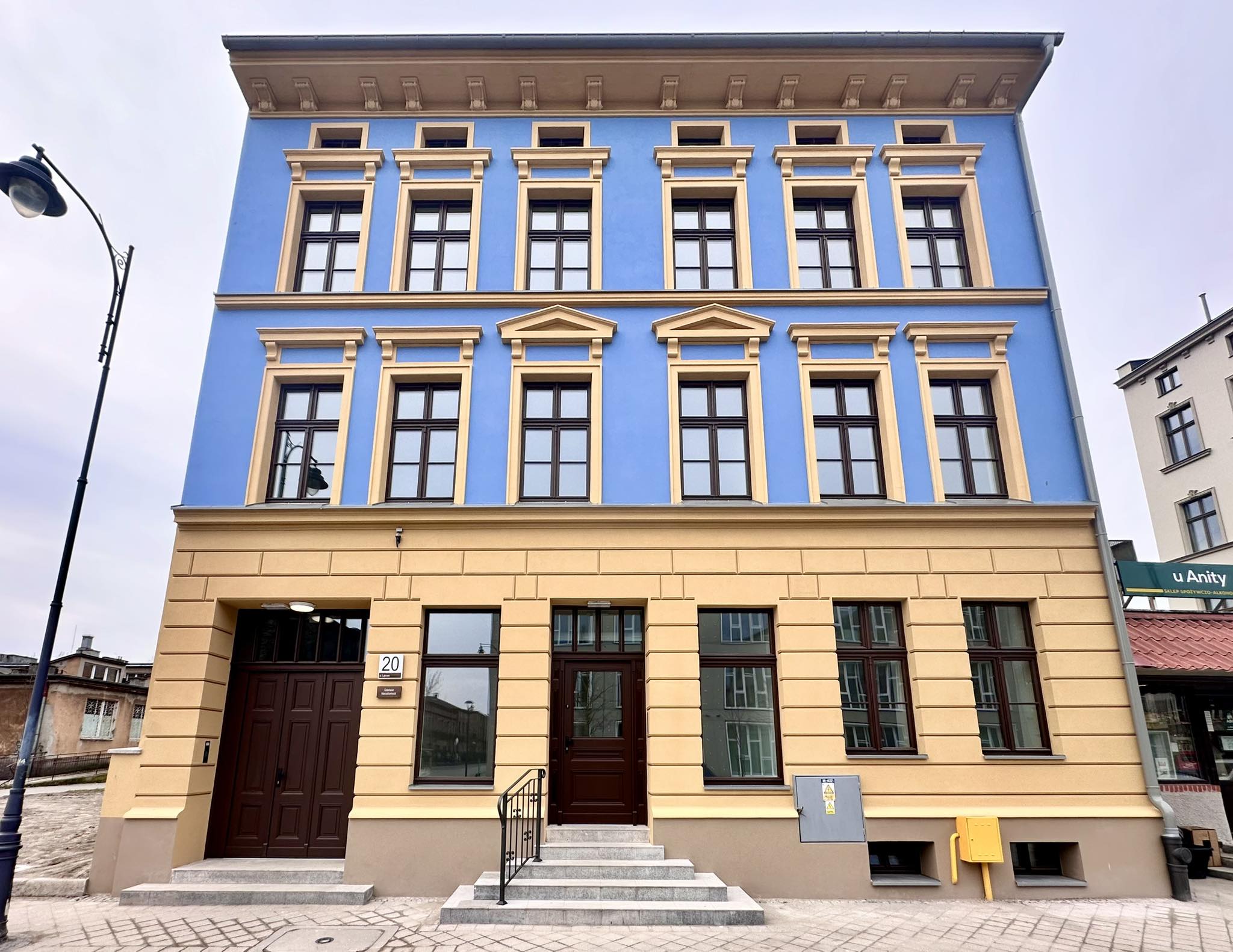 Zdjęcia przedstawia budynek po modernizacji przy ul. Łąkowej 20. Bogato zdobiona, odrestaurowana elewacja w intensywnych odcieniach żółci i błękitu.