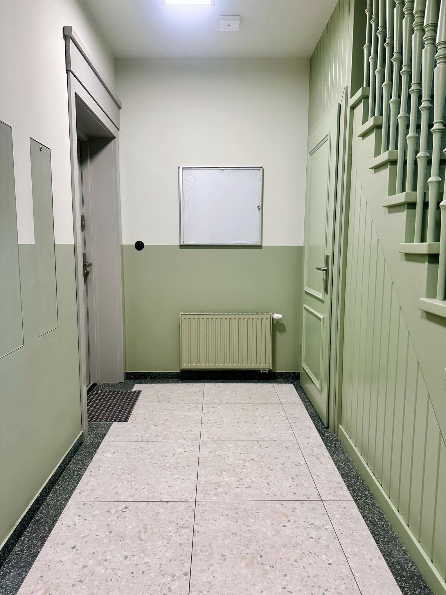 Zdjęcie przedstawia klatkę schodową w odcieniach zieleni i szarości