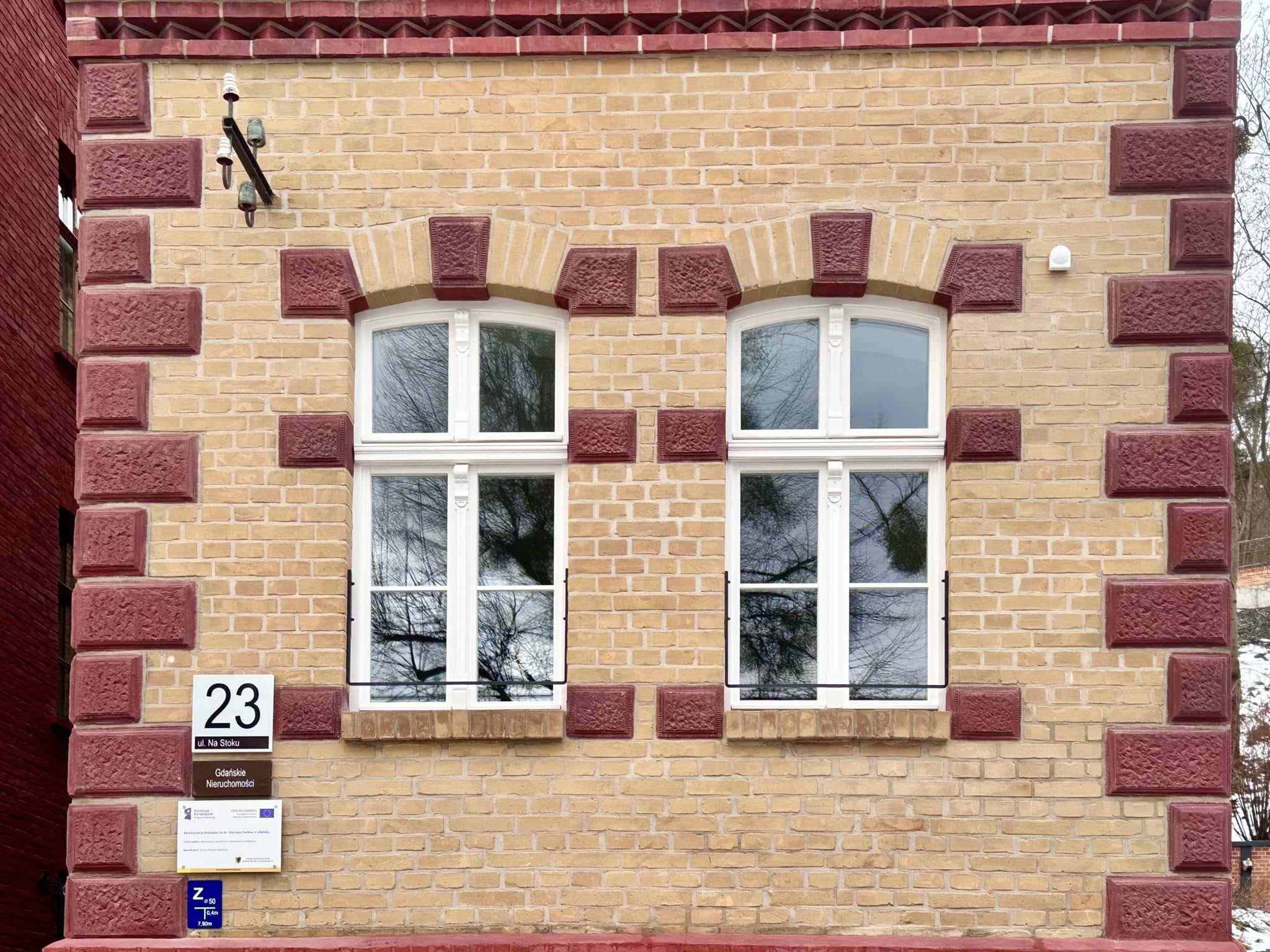 Zdjęcie przedstawia elewację budynku przy ul. Na Stoku 23 w kolorach żółtym i bordowym