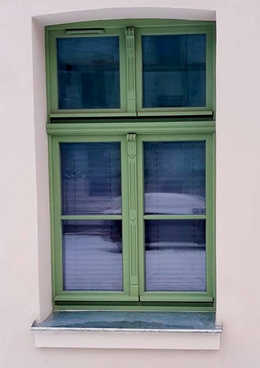 Na głównym planie znajduje się nowa stolarka okienna w kolorze zielonym.