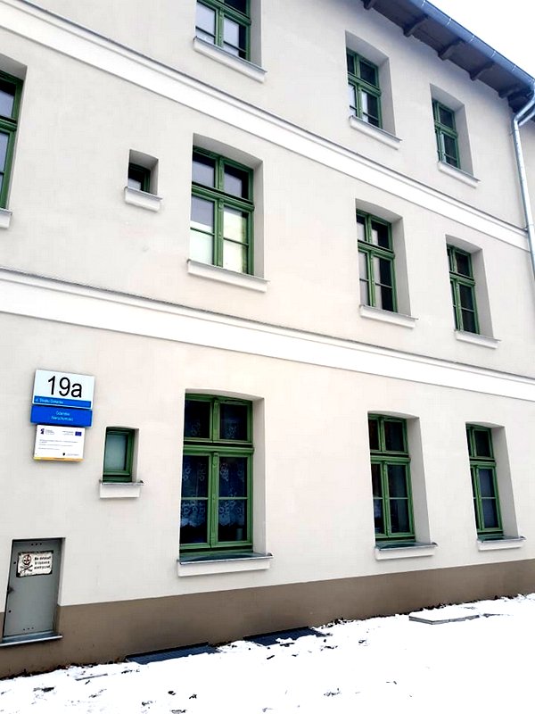 Zdjęcie przedstawia budynek pom Rewitalizacji. Nową elewację, wymieniona stolarkę okienna i tablice numeryczną.